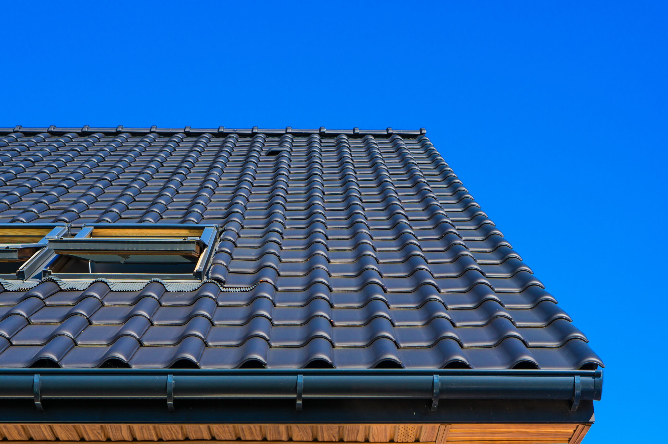 Vertical low angle closeup shot of the black roof of a building with a blue background